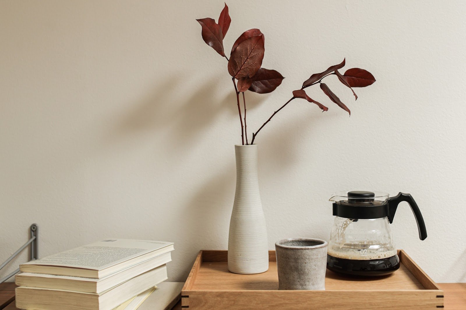 coffee pot next to a vase and a stack of books