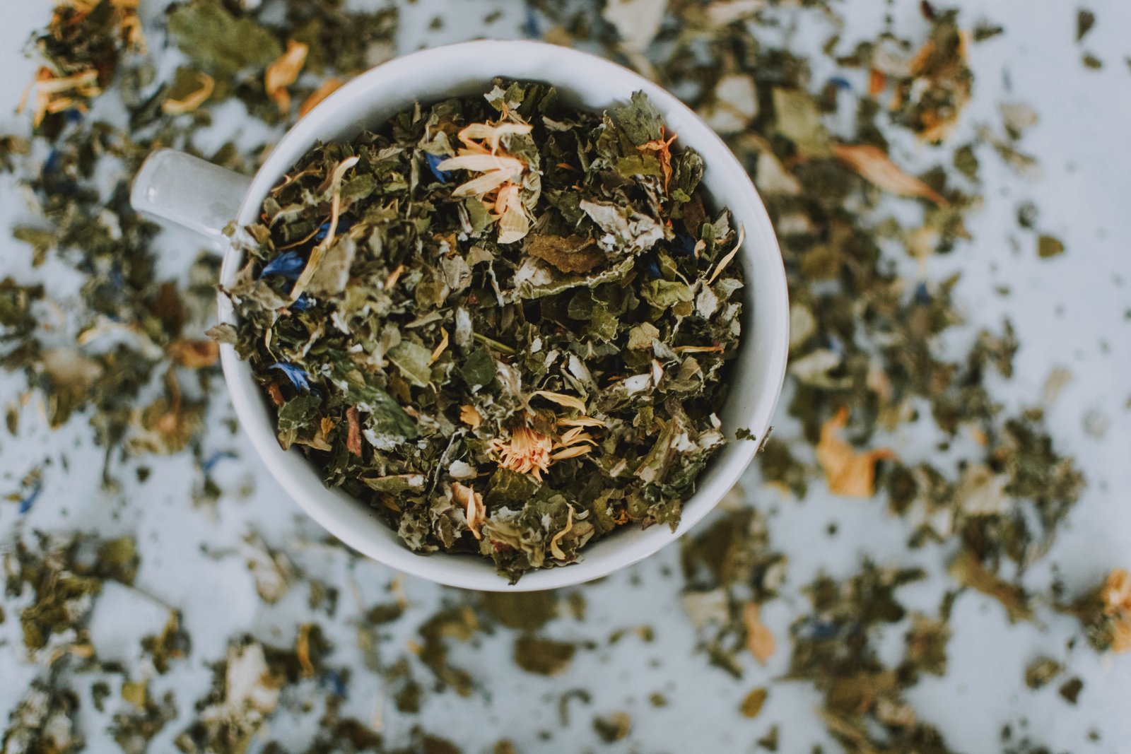 a white mug overflowing with dried herbs